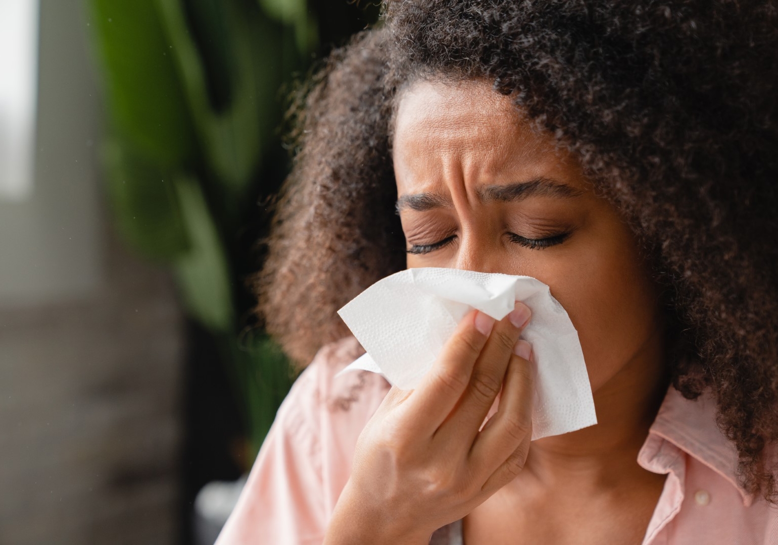 African American woman sneezing into a tissue